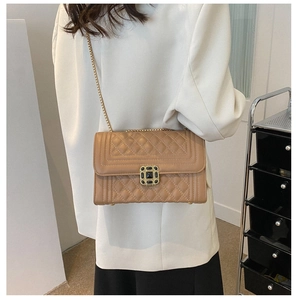 Detail of tan quilted crossbody bag with gold square buckle worn over a white blazer