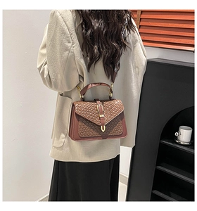 Detail of brown woven and crocodile texture handbag with decorative canvas strap