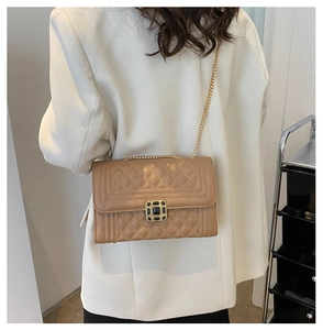 Detail of light camel quilted crossbody bag featuring gold chain and metal buckle
