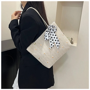 Détail du sac cabas en paille beige avec broderie marguerite et foulard à pois