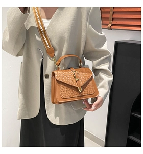 Detail of brown crocodile pattern shoulder bag with a geometric woven wide strap
