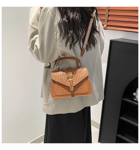 Detail of vintage brown textured crossbody bag with a geometric woven wide strap
