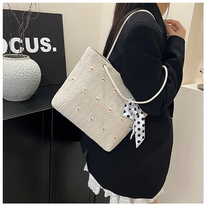 Chic beige woven tote bag with daisy embroidery and polka dot scarf shown on a model