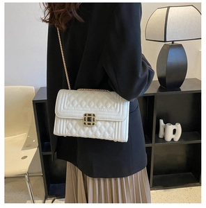 Close-up of white quilted leather texture and golden metal chain on crossbody bag