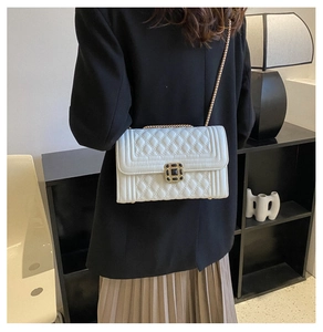 Detail of white quilted crossbody bag with gold chain and vintage square metal lock
