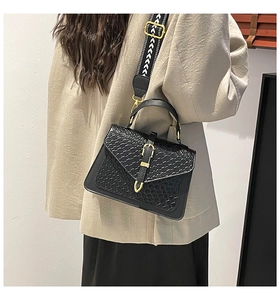 Detail of black woven texture crossbody bag with wide geometric strap and gold buckle