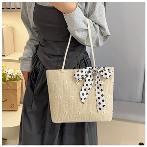 Détail du sac cabas en paille avec broderie de marguerites et ruban à pois