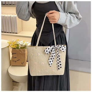 Détail du sac cabas tissé avec broderie de marguerites blanches et nœud en soie à pois
