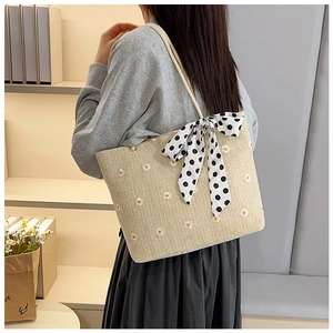 Détail du sac cabas tissé avec broderie de marguerites et nœud à pois élégant