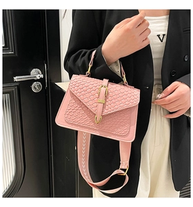 Detail view of pink textured crossbody bag with woven crocodile pattern and wide strap