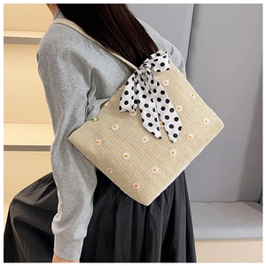 Détail du sac cabas en paille avec broderies marguerites et nœud à pois noirs