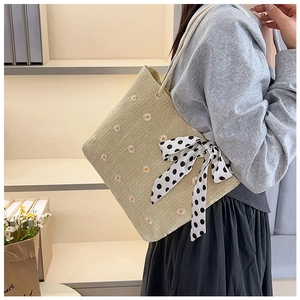 Straw tote bag featuring daisy embroidery and a polka dot bow ribbon detail