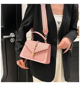 Pink woven texture shoulder bag with gold clasp and broad patterned strap shown on a model