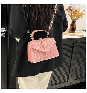 Detail of pink woven texture crossbody bag with gold buckle on a stylish model