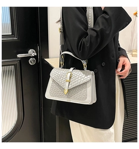 Detail of grey crossbody bag with stone texture, wide woven strap and golden buckle clasp