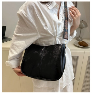 Detail of black patent leather crossbody bag with colorful jacquard wide strap