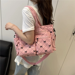 Pink corduroy tote bag with black bow patterns and multiple functional pockets on model