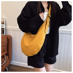 Detail of yellow lychee texture leather crescent bag with adjustable wide strap on model