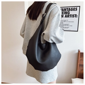 Side view of a large black lychee textured hobo bag with adjustable silver buckle strap