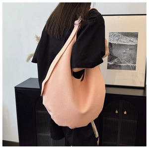 Macro view of the pink lychee grain leather texture and wide shoulder strap on hobo bag