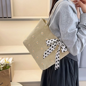 Beige woven straw tote bag with daisy embroidery and black polka dot bow detail