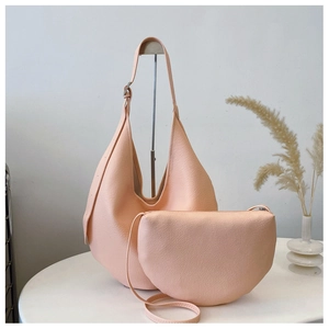 Detail of pink lychee leather bucket bag and small crossbody bag set in minimalist setting