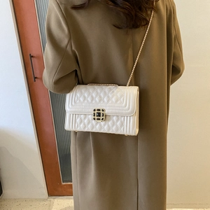 Quilted white shoulder bag with gold chain and vintage clasp worn by model in a bright room