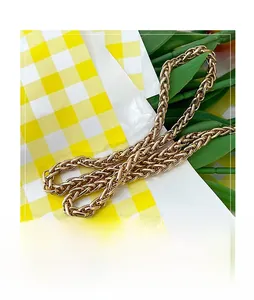 Close-up of golden metal woven chain detail on a summer fashion bucket bag strap