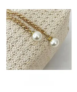 Detail of woven gold chains with large white pearls and crystal spacers on a bucket bag