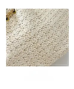 Close-up of beige woven texture and elegant gold metal chain on a crossbody bucket bag
