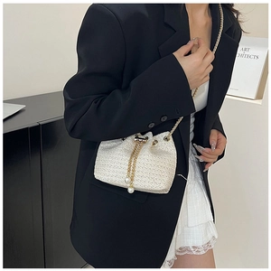 Detail of woven straw bucket bag with gold chain and white pearl drawstring charms