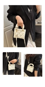 Detail of white quilted mini bag with gold chain strap and elegant top handle texture