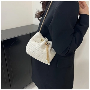 Detail of cream woven bucket bag with gold chain strap and pearl drawstring tassels
