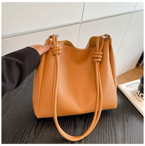 Détail du cabas en cuir caramel avec bandoulière en corde tressée et design noué