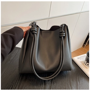 Détail du grand sac cabas en similicuir noir avec un design de sangle à gros nœud