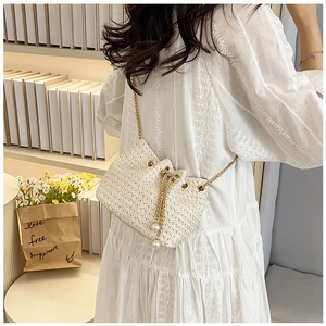 Detail view of woven bucket bag with pearl tassels and golden metal chain strap