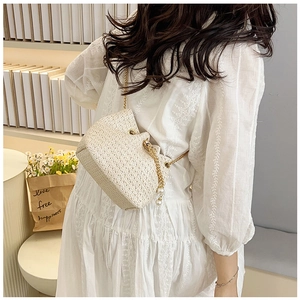 Detailed weave of light beige straw bucket bag featuring elegant large pearl charms