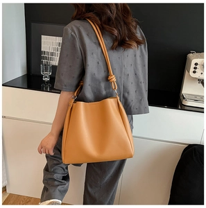 Détail du sac à bandoulière en cuir camel avec un design de sangle nouée unique sur l'épaule