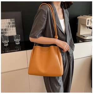 Détail du sac seau jaune minimaliste avec nœuds sur les bandoulières cylindriques