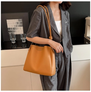 Détail du sac cabas en cuir mat jaune gingembre avec bandoulière nouée porté par mannequin
