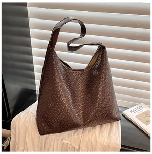Detailed view of dark brown woven tote bag featuring soft synthetic leather and wide strap