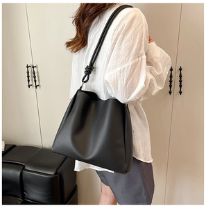 Détail d'un sac cabas noir en similicuir avec bandoulière nouée et finition mate élégante