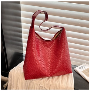 Macro detail of red woven leather tote bag with elegant texture on white fabric