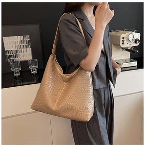 Detail of woven leather texture on a beige oversized hobo bag with wide shoulder strap
