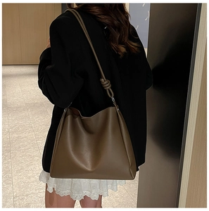 Grand sac hobo en cuir souple marron avec détail de nœud porté par un mannequin
