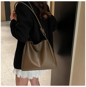 Détail d'un sac cabas en cuir marron olive avec une bandoulière à nœud au design élégant