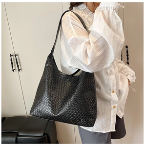 Detail of black woven shoulder bag with large lattice texture on leather tote bag