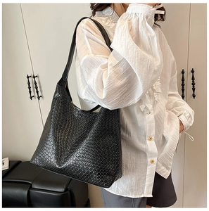 Detail of the high-quality black woven leather texture on a spacious tote shoulder bag