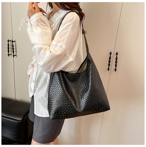 Detail of a large black woven leather tote bag showing intricate checkered texture and style
