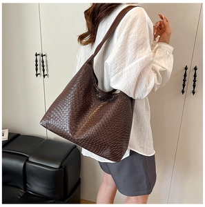 Close-up of the woven leather texture and spacious interior of the brown tote bag